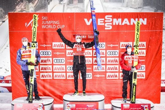 Halvor Egner Granerud (M) jubelt auf dem Podium nach seinem Sieg mit dem Zweiten, Karl Geiger (l) und dem Drittplatzierten Stefan Kraft.