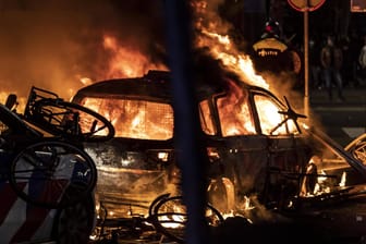 Ein Auto brennt in Rotterdam: Bei schweren Ausschreitungen hat es nach Schüssen der Polizei Verletzte gegeben.