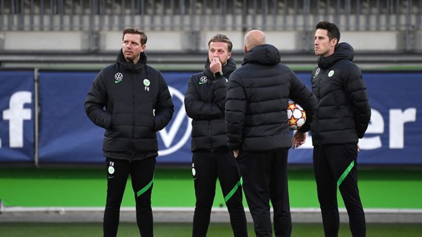 Vor dem Abflug nach Sevilla war Corona wieder ein Thema: Wolfsburgs Trainer Florian Kohfeldt (l) steht mit seinem Team zusammen.