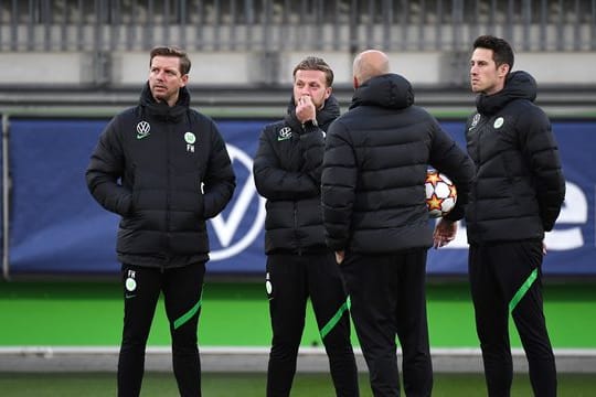 Vor dem Abflug nach Sevilla war Corona wieder ein Thema: Wolfsburgs Trainer Florian Kohfeldt (l) steht mit seinem Team zusammen.