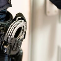 Handschellen sind an einem Gürtel eines Justizvollzugsbeamten befestigt (Symbolbild): Gegen den Mann lag ein Haftbefehl vor.