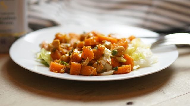 Der herzhafte Salat aus Süßkartoffeln, Kichererbsen und Möhren wird auf Eisbergsalat angerichtet.