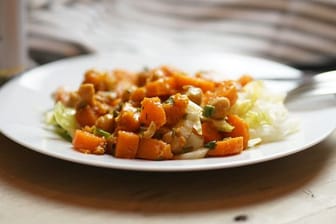 Der herzhafte Salat aus Süßkartoffeln, Kichererbsen und Möhren wird auf Eisbergsalat angerichtet.