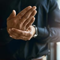Mann massiert sich die Hand: Eine rheumatoide Arthritis beginnt oft mit Schmerzen in den Hand- oder Fingergelenken.
