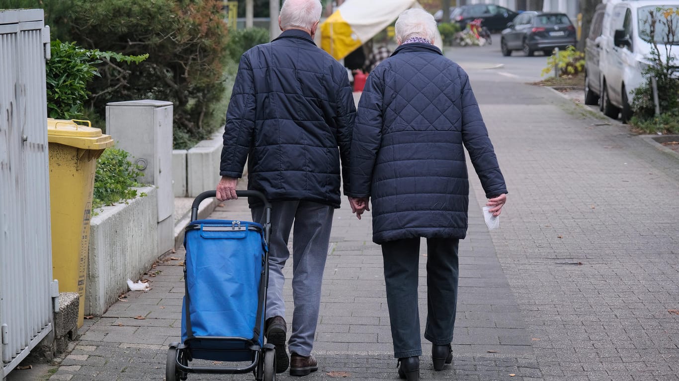 Ein Rentnerpaar läuft an einer Straße entlang (Symbolbild): Die Renten in Deutschland werden wohl geringer steigen als erwartet.