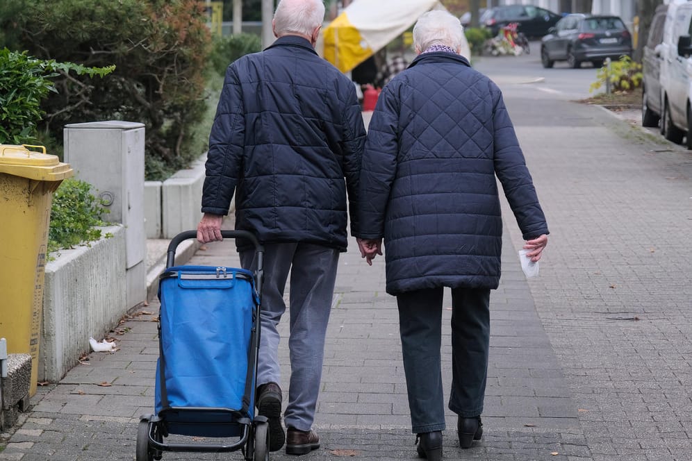Ein Rentnerpaar läuft an einer Straße entlang (Symbolbild): Die Renten in Deutschland werden wohl geringer steigen als erwartet.