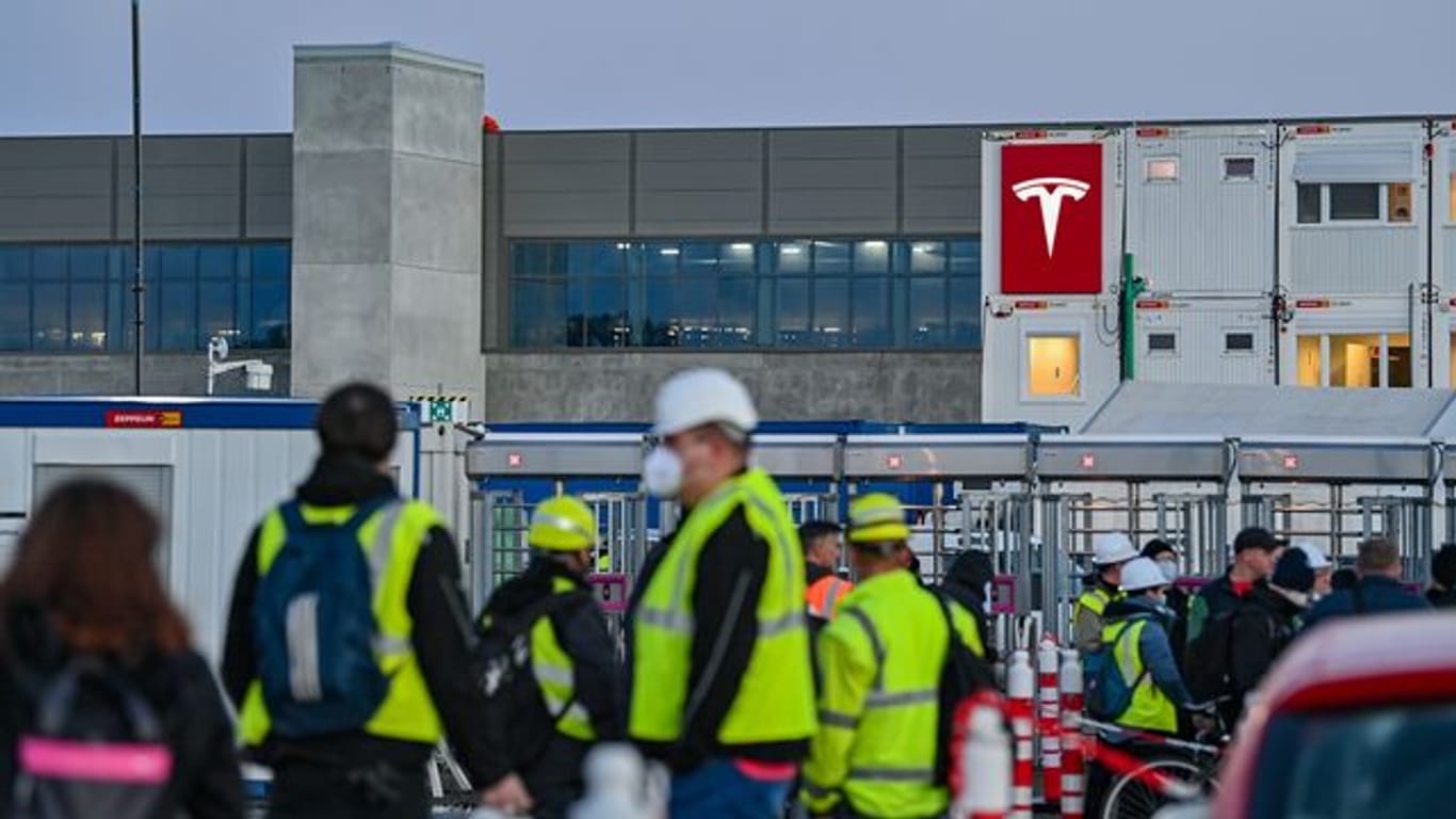 Arbeiter vor dem Tesla-Sitz in Grünheide: Der Fabrik fehlt noch eine Genehmigung für den Bau der Autos.