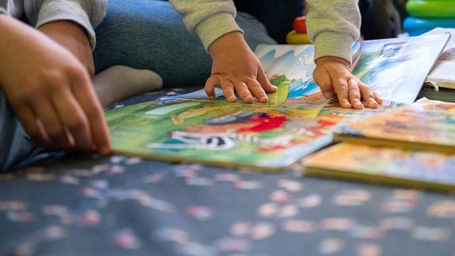Eine Erzieherin liest in der Kita einem Mädchen vor Eine Erzieherin liest in der Kita einem Mädchen vor