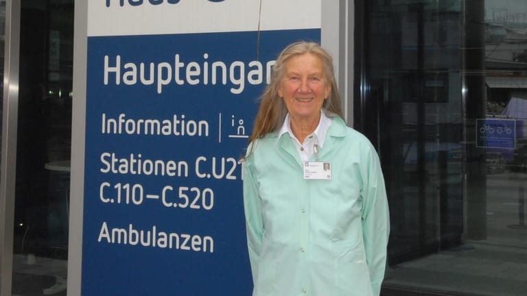 Wilma Jessen vor einem Schild am UKSH: Die 71-Jährige ist seit zehn Jahren bei den "Grünen Engeln".