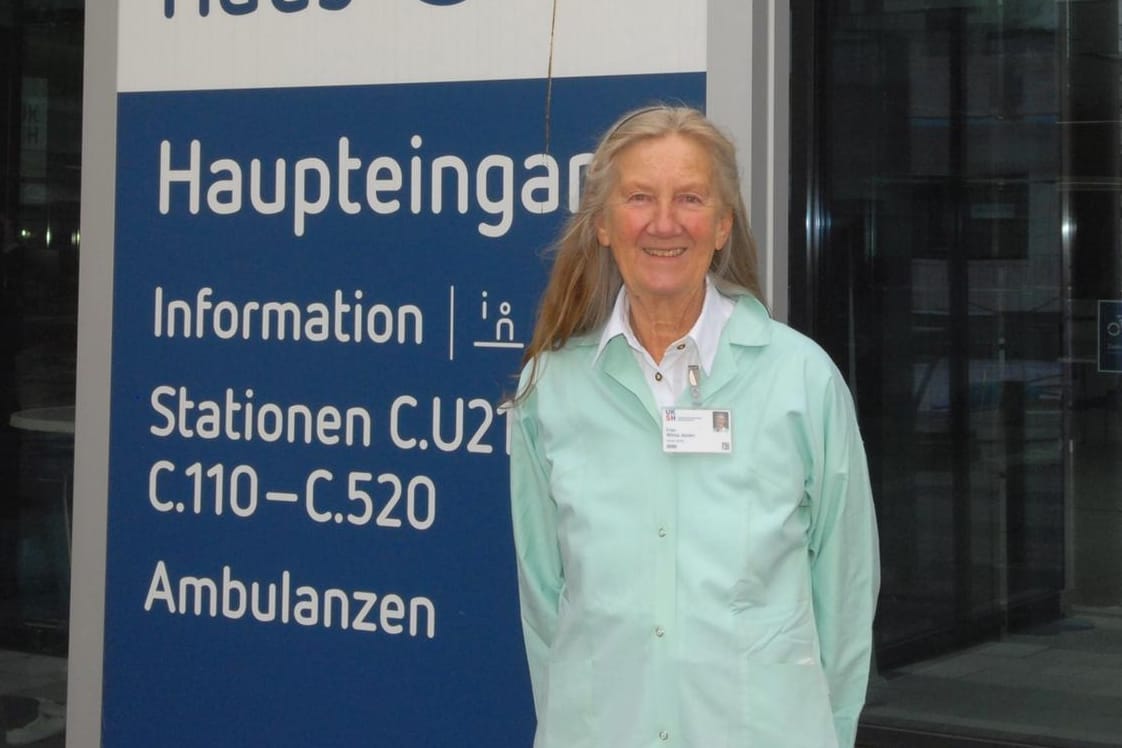 Wilma Jessen vor einem Schild am UKSH: Die 71-Jährige ist seit zehn Jahren bei den "Grünen Engeln".