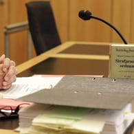 Die Strafprozessordnung und Akten liegen auf einem Pult im Gerichtssaal (Symbolbild): In Köln ist ein 27-Jähriger wegen sexueller Nötigung und Körperverletzung angeklagt.