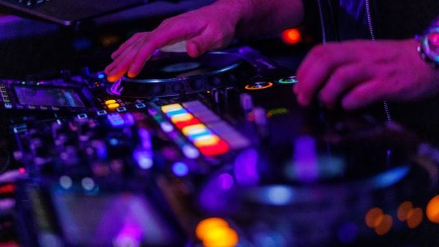 Ein DJ steht in einem Club am Mischpult