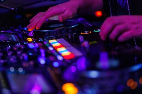 Ein DJ steht in einem Club am Mischpult