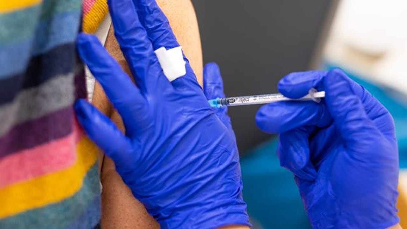 Die Mitarbeiterin eines Impfzentrums impft eine Frau gegen Corona