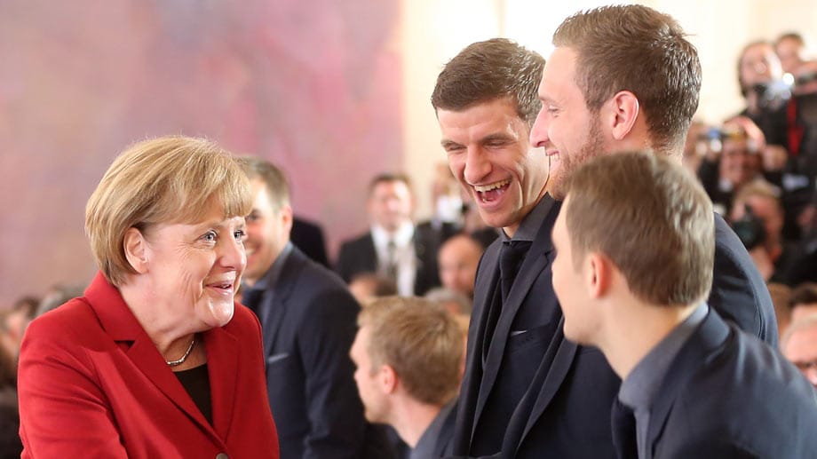 Thomas Müller (3.v.re.) und Shkodran Mustafi (2.v.re.) haben sichtlich Spaß bei der Begrüßung durch Angela Merkel (li.). Die Kanzlerin gehörte zu den ersten Gratulanten nach dem gewonnen Titel. Vielleicht ist die Begegnung in der Kabine jader Grund warum Müller hier so lachen muss.