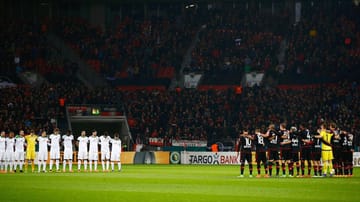 Vor der Partie Bayer Leverkusen gegen Werder Bremen gedenken die beiden Mannschaften in einer Schweigeminute den Opfern des Zugunglücks bei Bad Aibling.