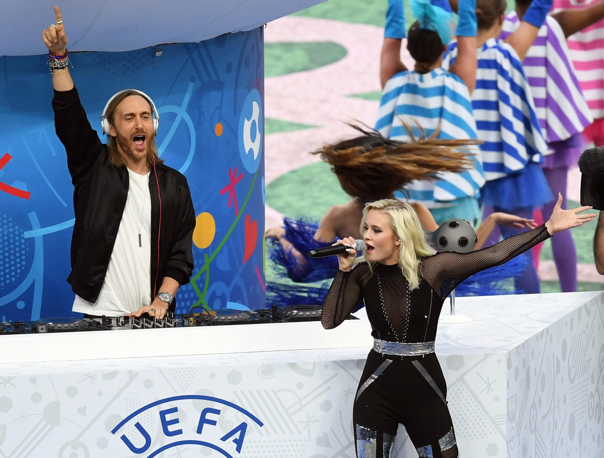 Dann taucht David Guetta (li.) aus einem riesigen Karussell im Mittelkreis auf und heizt dem Publikum ein. Zusammen mit der schwedischen Sängerin Zara Larsson gibt der französische Star-DJ den EM-Song "This One's For You" zum Besten.
