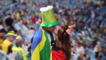 Vor der Eröffnungsfeier tauschen ein brasilianischer Fan und eine Anhängerin des deutschen Teams einen Kuss aus.
