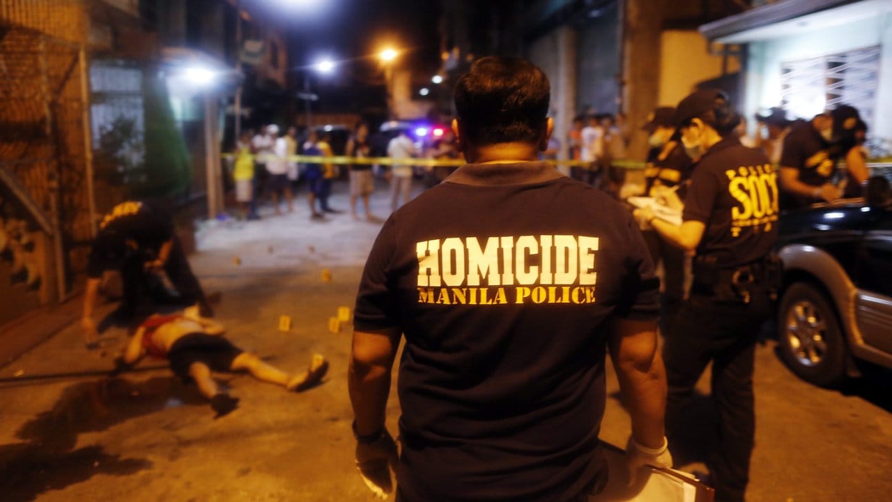 Philippinische Polizisten untersuchen die Leiche eines mutmaßlichen Drogendealers, der in Manila von einem Unbekannten erschossen wurde.