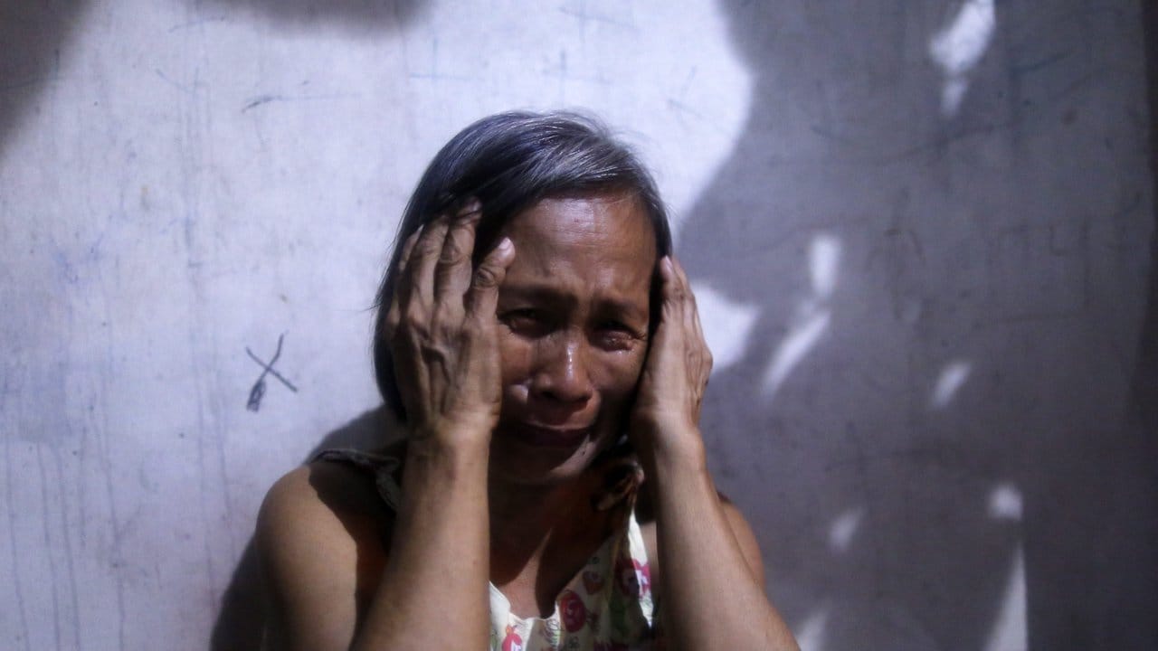 Eine Philippinerin trauert um einen Verwandten, der von einem unbekannten Killer in Manila erschossen wurde.