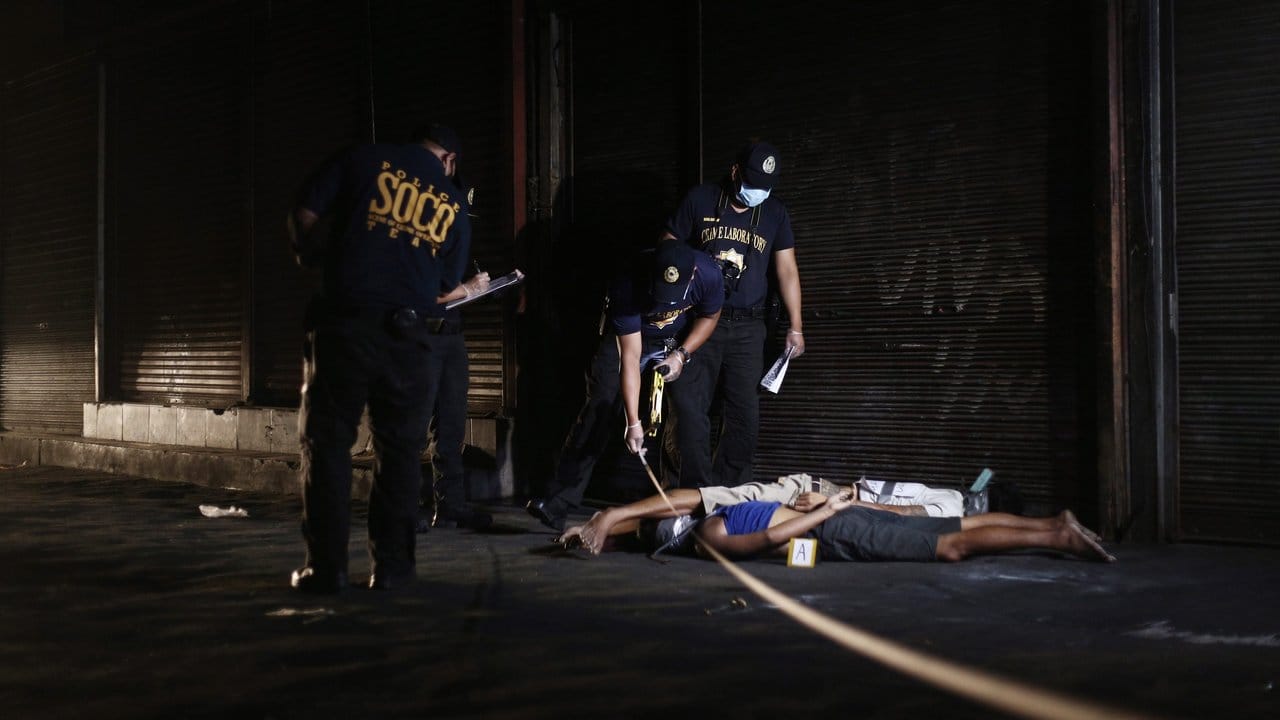 Polizisten untersuchen in Manila die Leichen zweier mutmaßlicher Drogenhändler.