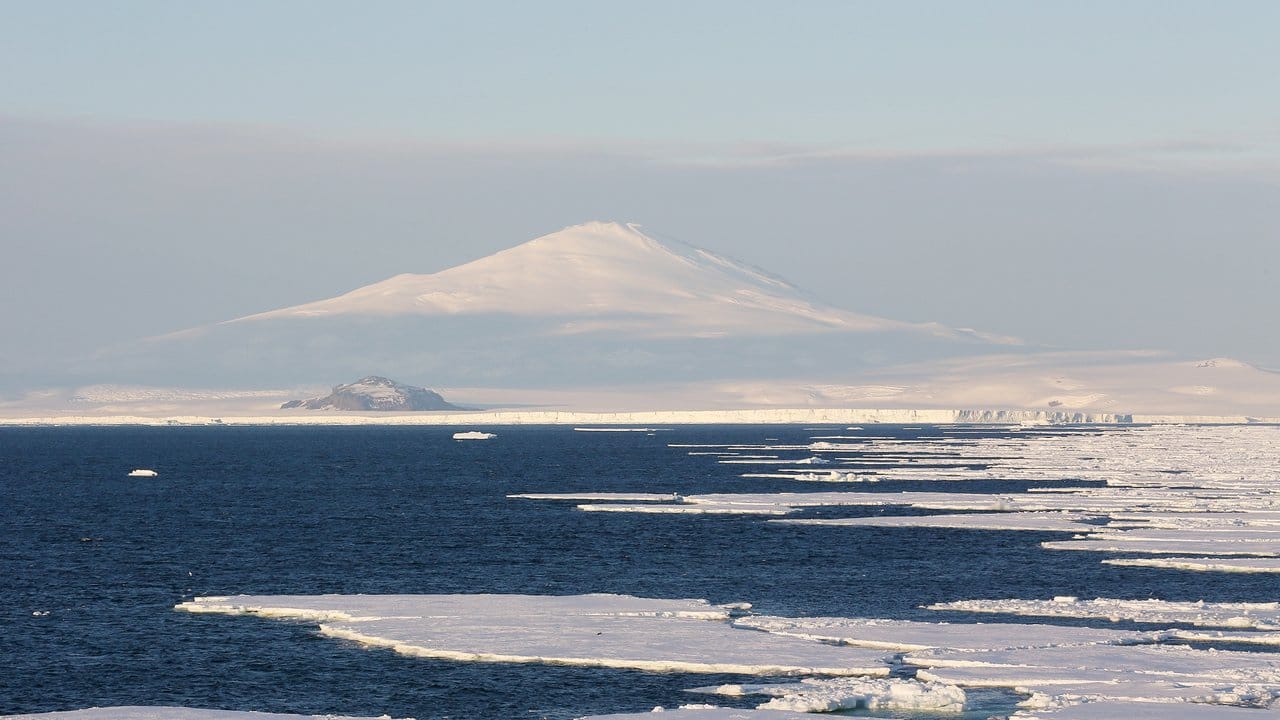 Der Mount Melbourne ragt hinter Eisschollen im Meer am westlichen Rand des Rossmeers in der Antarktis in den Himmel.