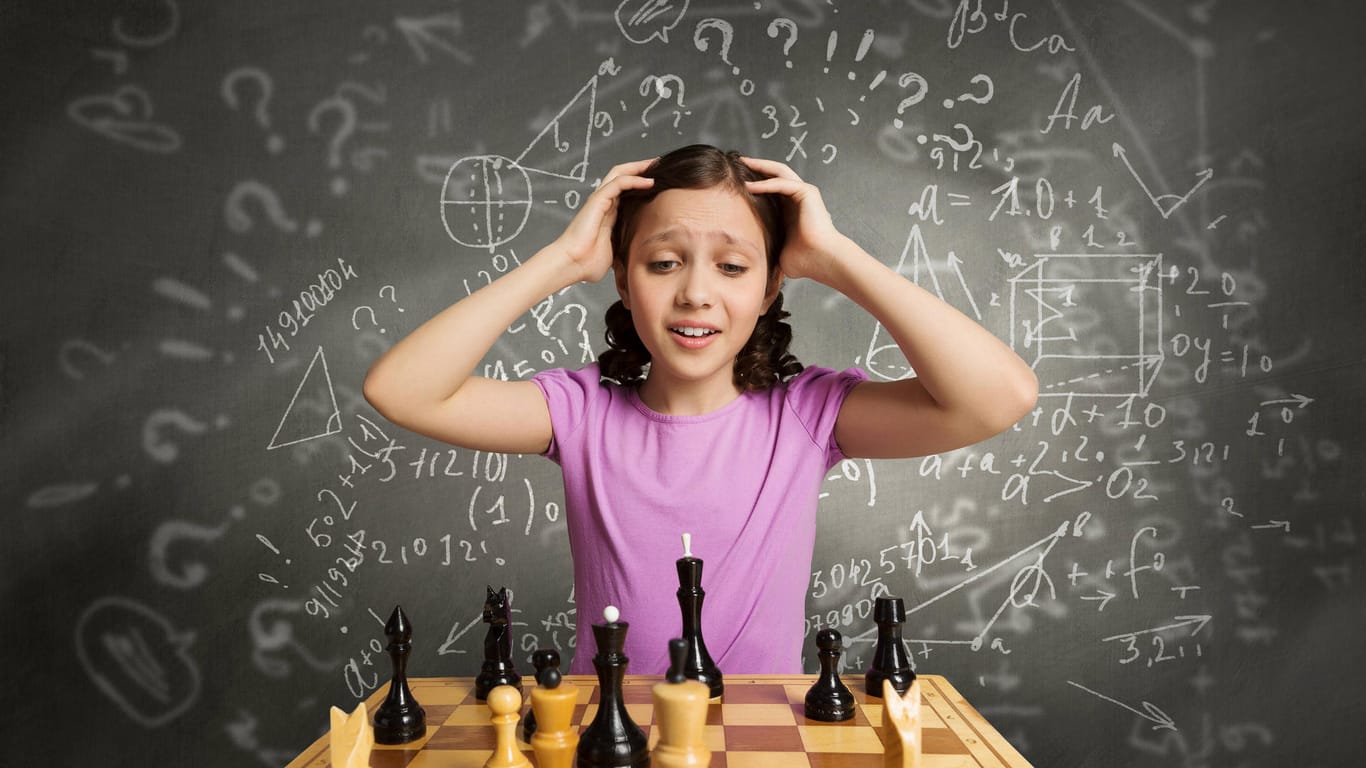 Ein junges Mädchen schaut auf ein Schachbrett und rauft sich die Haare.