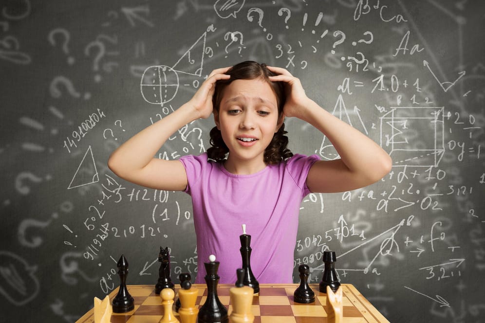 Ein junges Mädchen schaut auf ein Schachbrett und rauft sich die Haare.