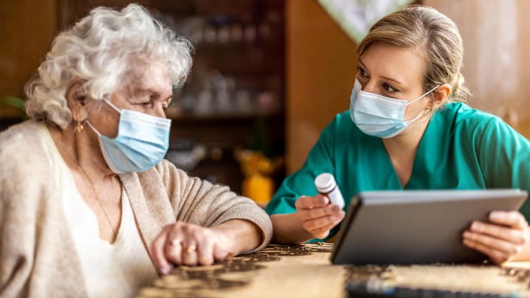 Eine Pflegerin hilft einer Seniorin mit ihren Medikamenten (Symbolbild): Ab Januar 2022 gibt es von der Pflegeversicherung einen Zuschuss zum Eigenanteil der stationären Pflegekosten.