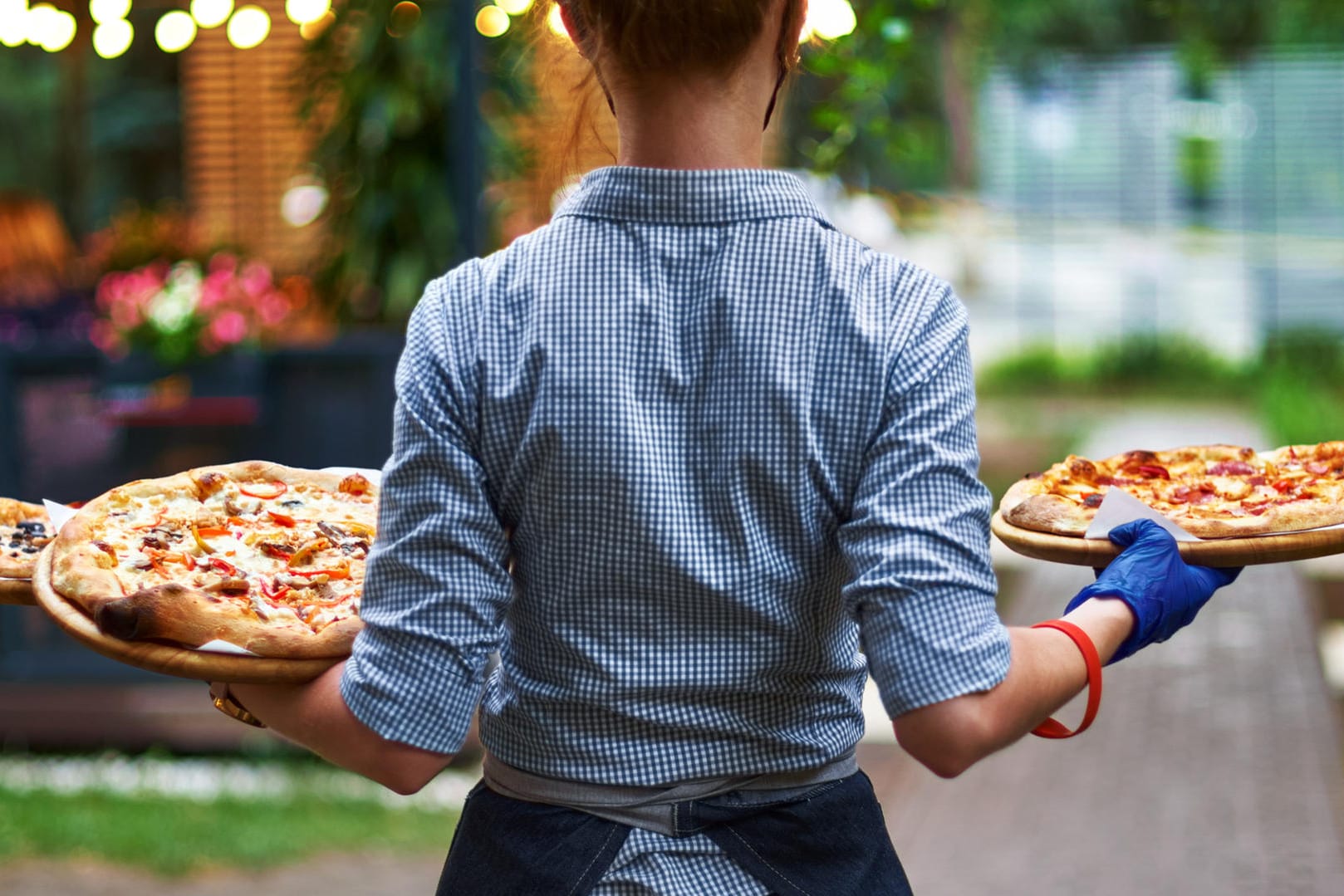 Eine Kellnerin bringt Gästen Pizza (Symbolbild): Wer den Mindestlohn bekommt, kann sich ab Januar über etwas mehr Einkommen freuen.