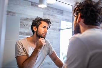 Mann betrachtet sich im Spiegel