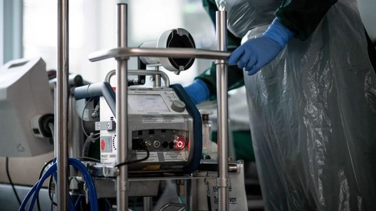 Eine Pflegekraft steht auf einer Intensivstation in einem Zimmer und bedient eine Herz-Lungen-Maschine. (Symbolbild)