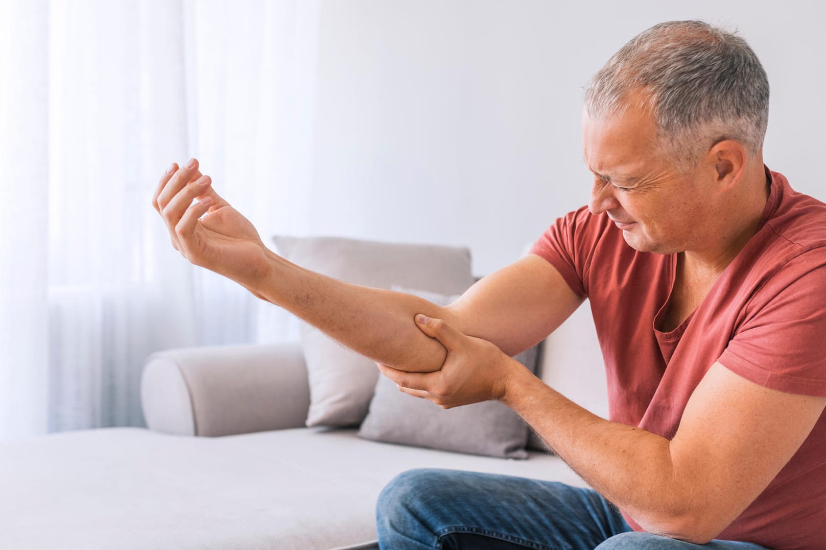 Ein Mann fasst sich wegen Schmerzen an seinen Unterarm: Fehlen dem Körper Mineralstoffe, wie Magnesium, Kalium oder Kalzium können Muskelschmerzen die Folge sein.