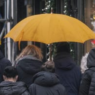 Fußgänger mit Regenschirm (Symbolbild): In vielen Teilen Deutschlands bleibt es grau, Sturmtief "Daniel" soll starke Böen und viel Niederschlag bringen.