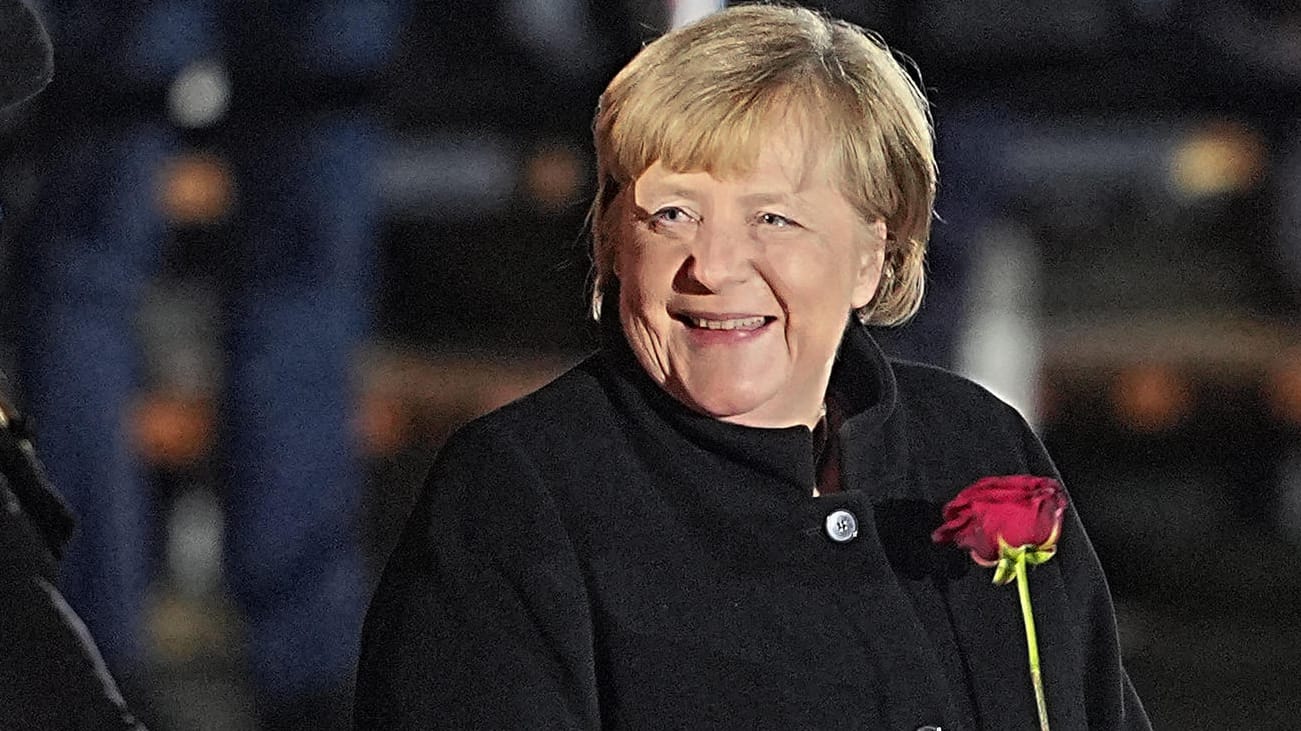 Angela Merkel: Nach ihrer Verabschiedung lacht die Bundeskanzlerin mit einer Rose in der Hand.