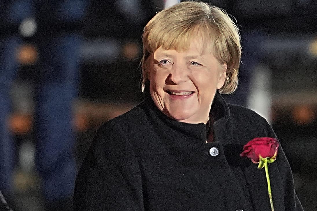 Angela Merkel: Nach ihrer Verabschiedung lacht die Bundeskanzlerin mit einer Rose in der Hand.