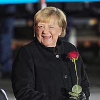 Angela Merkel: Nach ihrer Verabschiedung lacht die Bundeskanzlerin mit einer Rose in der Hand.