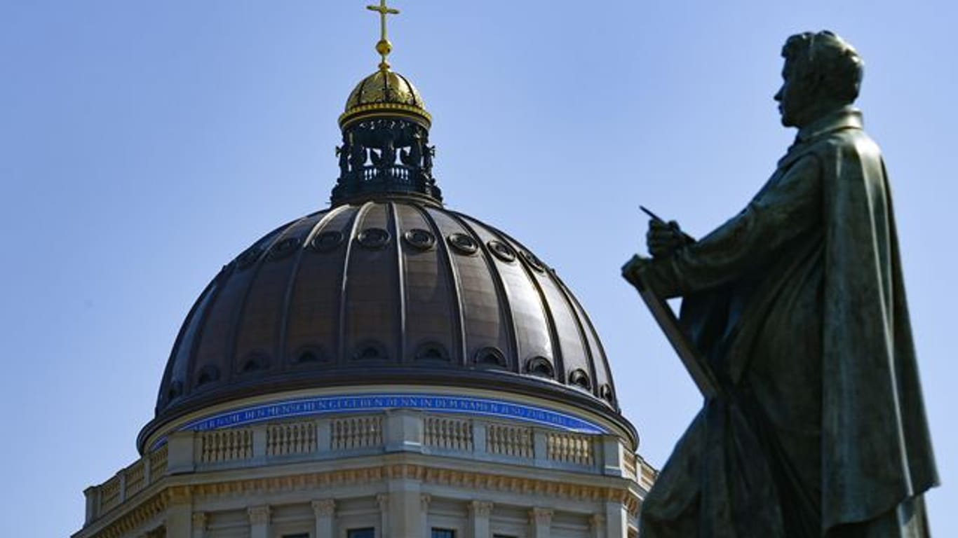 Die Skulptur von Karl Friedrich Schinkel ist vor der Kuppel vom Humboldt Forum in Berlin Mitte zu sehen.