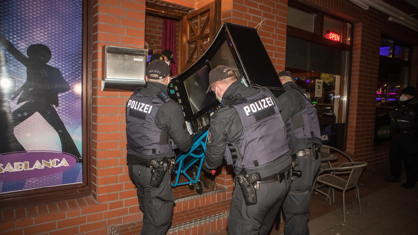 Polizeikräfte schaffen einen Spielautomaten aus einem durchsuchten Lokal: Das eigentliche Ziel der Razzia war illegales Glücksspiel.