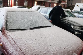 Schnee in Hamburg: Ein Mann befreit sein Auto am Samstagmorgen von einer dünnen Schneedecke.