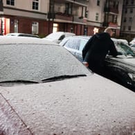 Schnee in Hamburg: Ein Mann befreit sein Auto am Samstagmorgen von einer dünnen Schneedecke.