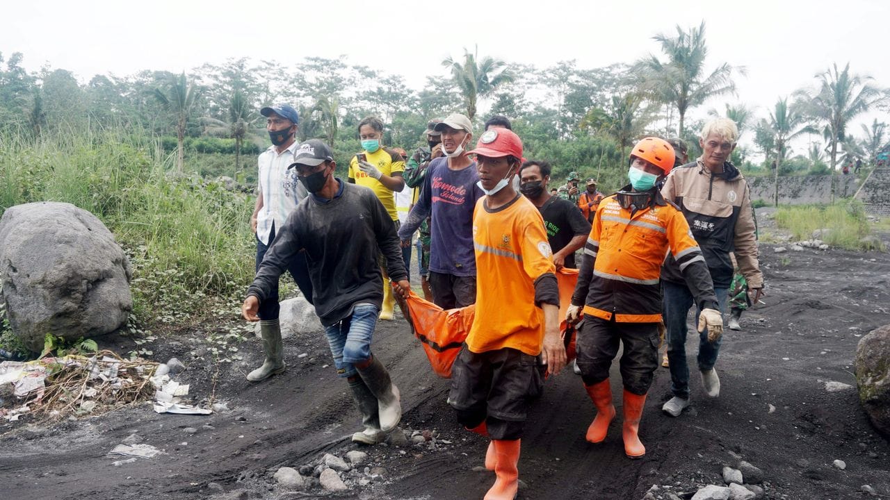 Rettungskräfte tragen ein Opfer nach dem Vulkanausbruch des Mount Semeru im Krisengebiet.