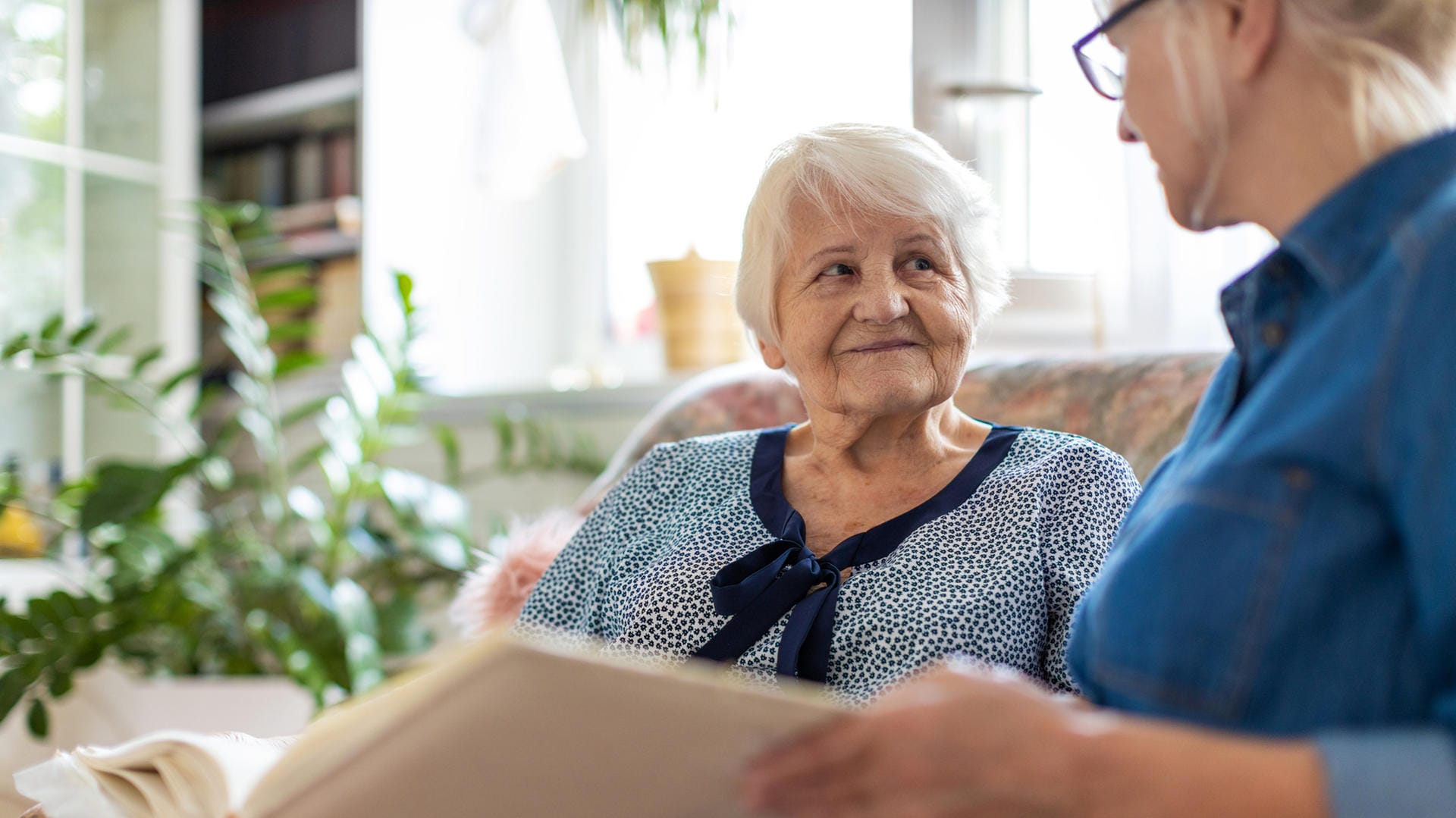 Eine Frau zeigt einer Seniorin ein Buch.