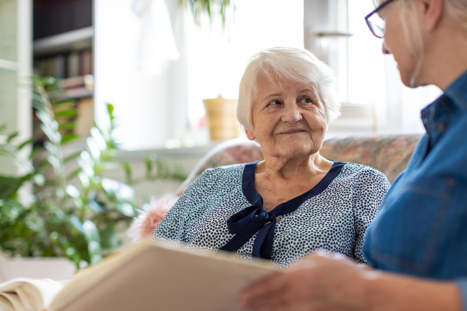 Eine Frau zeigt einer Seniorin ein Buch.