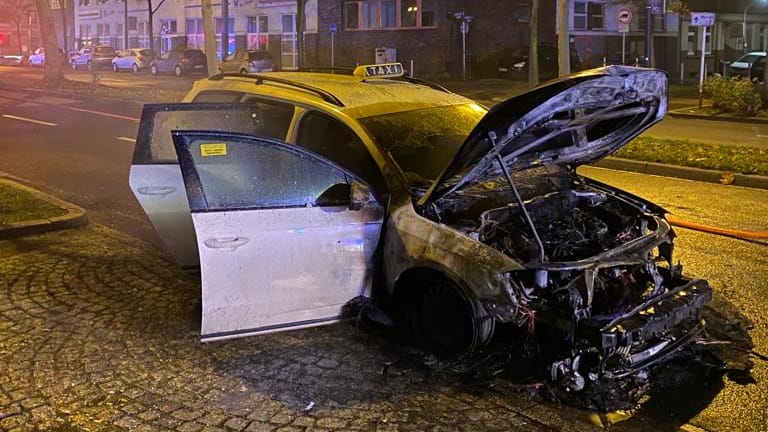 Das ausgebrannte Taxi auf der Straße: Die Insassen konnten sich unverletzt befreien.