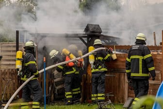 Feuerwehrmänner löschen einen Brand in einer Gartenhütte (Symbolbild): Der mutmaßliche Täter soll unter anderem in einer Gartenlaube Feuer gelegt haben.
