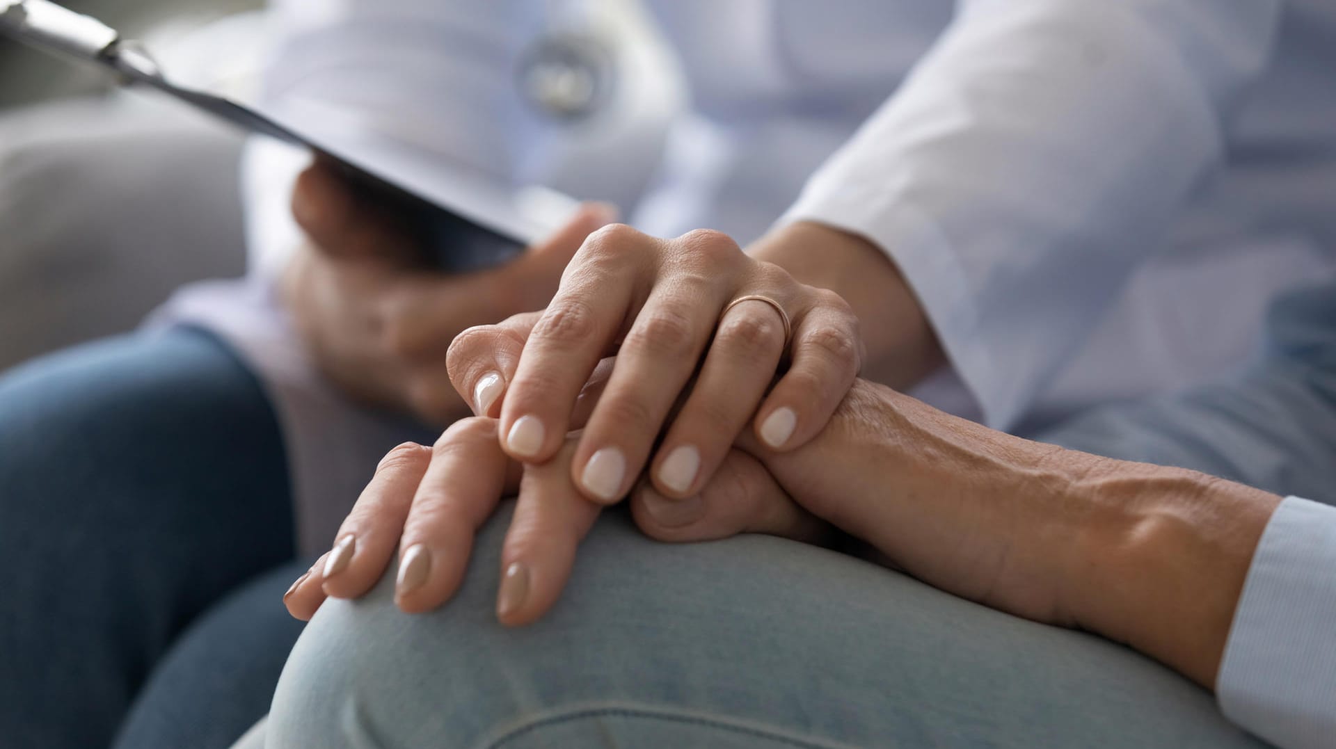 Young woman doctor holding hand of senior grandmother patient, closeup