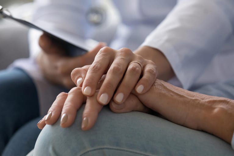 Young woman doctor holding hand of senior grandmother patient, closeup