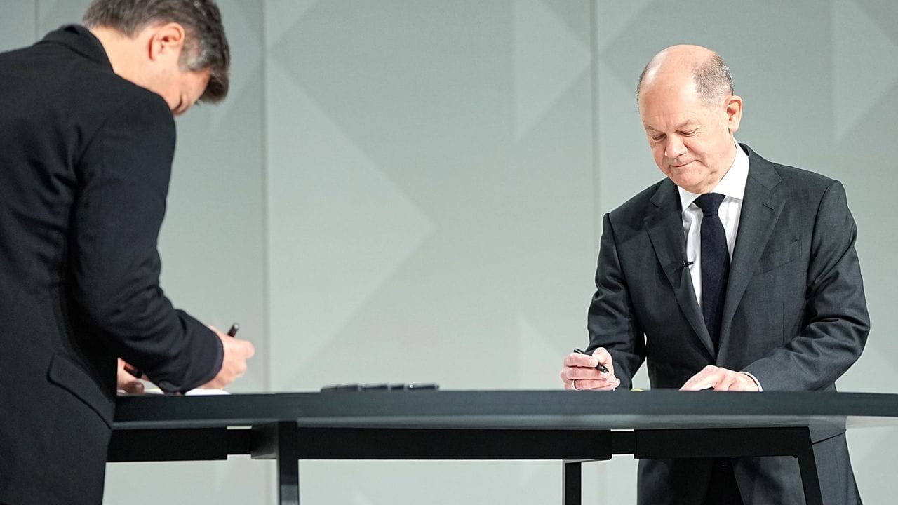 Der Grünen-Vorsitzende Robert Habeck (l) und der neue Kanzler Olaf Scholz (SPD) setzen ihre Unterschriften unter das Dokument.