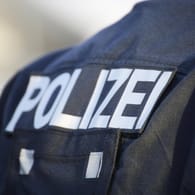 "Polizei" steht auf der Jacke eines Beamten (Symbolbild): In Berlin sind mehrere Personen festgenommen worden.